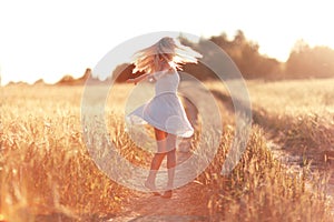 Happy girl on the road in a wheat field