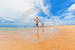 Happy girl run by wide sand beach