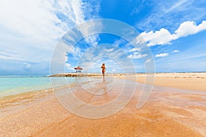 Happy girl run by wide sand beach