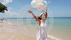 Happy girl running on the beach, holding balloons in hand. slow motion. Concept happiness, freedom, vacation, love