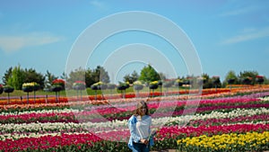 Happy girl running on floral background outdoors. Young woman in tulip field.