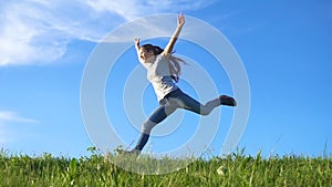 Happy girl running on green grass hill against blue sky