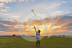 Happy girl running with a kite at sunset outdoors