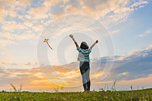 Happy girl running with a kite at sunset outdoors