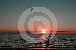 happy girl running with a kite at sunset outdoors. A child runs with a kite at sunset against the backdrop of the sea