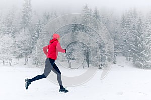Happy girl running on snow in winter mountains. Sport, fitness inspiration and motivation. Young happy woman trail running in