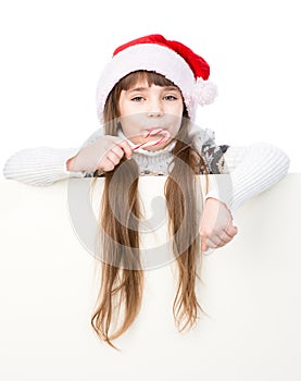 Happy girl in santa hat with Christmas candy cane standing behin behind banner. on white