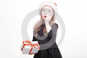 Happy girl in santa hat with gift on white background. Funny young child waiting for christmas, new year and presents. holiday,