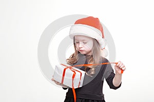 Happy girl in santa hat with gift on white background. Funny young child waiting for christmas, new year and presents. holiday,