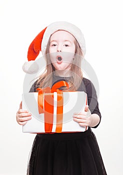 Happy girl in santa hat with gift on white background. Funny young child waiting for christmas, new year and presents. holiday,