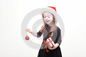 Happy girl in santa hat with gift on white background. Funny young child waiting for christmas, new year and presents. holiday,