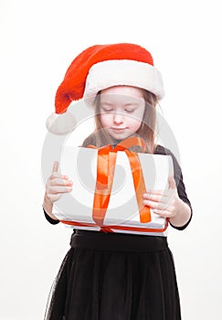 Happy girl in santa hat with gift on white background. Funny young child waiting for christmas, new year and presents. holiday,