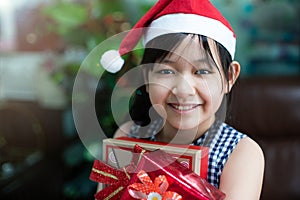 Happy girl in Santa red hat holding Christmas presen.Concept of Christmas and child