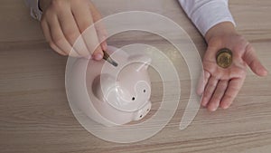 Happy girl save money in piggy bank in her home. Child inserting a coin into a piggy bank, indoor financial concept. Kid
