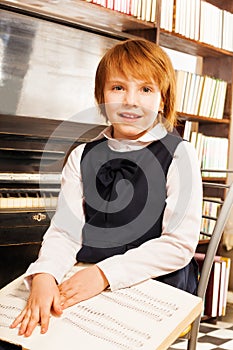 Happy girl in school uniform holding piano notes