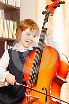 Happy girl in school uniform playing on the cello