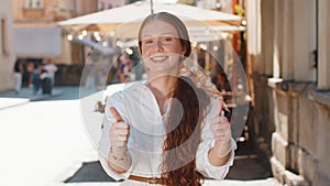 Happy girl showing thumbs up, like sign positive something good positive feedback in city street