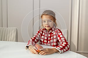 Happy girl sitting at white glass table with pear fruit in hads. concept of healthy eating