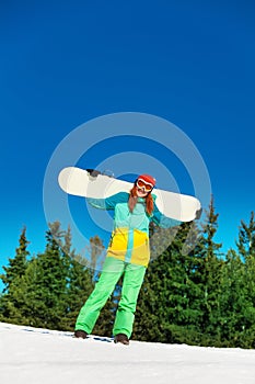 Happy girl in ski mask holding snowboard
