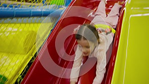 Happy girl sliding in red slide in amusment centre