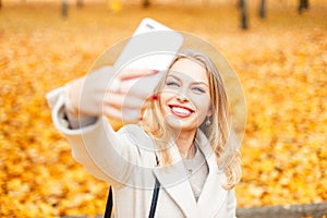 Happy girl with a smile doing selfie in a fall day against