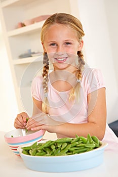 Happy girl splitting peas in kitchen