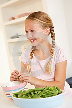 Happy girl splitting peas in kitchen