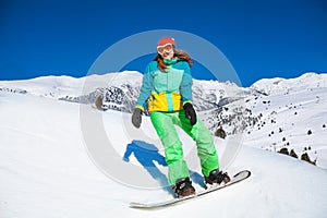 Happy girl standing on snowboard in mountains