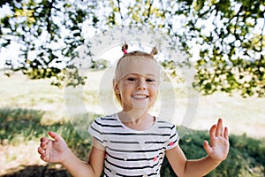 Happy girl in a striped dress smiles, shows teeth and looks at the camera