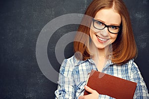 Happy girl student with glasses and book from blackboard