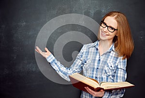 Happy girl student with glasses and book from blank blackboard