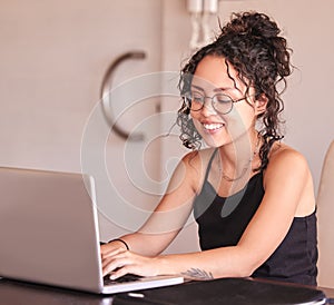 Happy girl, student and typing with laptop for research, browsing or communication on desk at home. Young writer or