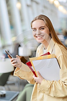 Happy girl student using mobile phone looking at camera, vertical portrait.