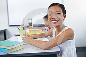 Happy girl studying at desk in in classroom