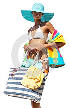 Happy girl in summer beach holiday wearing a bikini and blue sun hat holding beach bag and colorful towel, isolated on white