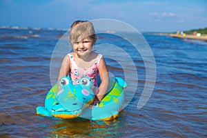 Happy girl swimming on an inflatable crocodile toy in the sea