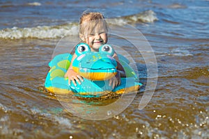Happy girl swimming on an inflatable crocodile toy in the sea