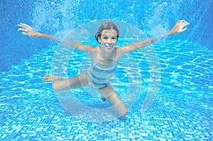 Happy girl swims in pool underwater, active kid swimming and having fun