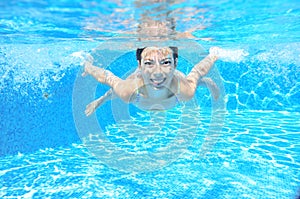 Happy girl swims in pool underwater, active kid swimming and having fun