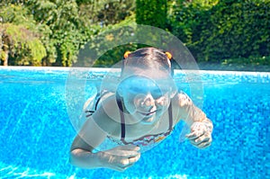 Happy girl swims in pool underwater, active kid swimming and having fun