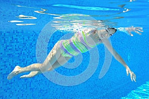 Happy girl swims underwater in pool