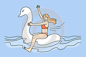 Happy girl in swimsuit float on rubber swan