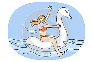 Happy girl in swimsuit float on rubber swan