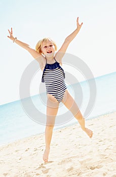Happy girl in swimsuit on seacoast jumping