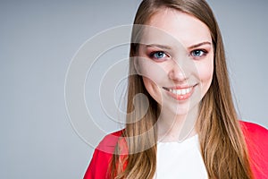 Happy girl in a T-shirt and sweater smiles broadly looking into the camera. Isolated on gray background photo