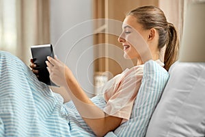 happy girl with tablet pc computer in bed at home