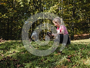 Happy girl with two dogs sitting on green grass having fun, family picnics, spending time together, hiking in mountains