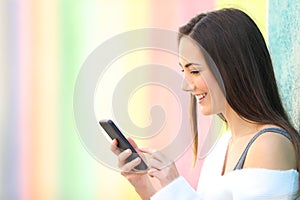 Happy girl uses a smart phone in a colorful street