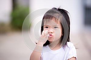 Happy girl is using her hand scratching her face and making a puckered up mouth in a good mood.