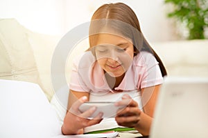 Happy girl using a mobile phone lying on the bed